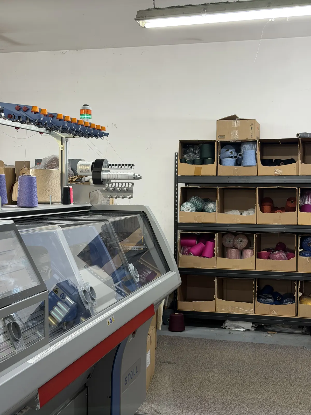 BerryBoat knitting mill floor in Łódź — flat-bed machines and yarn shelves