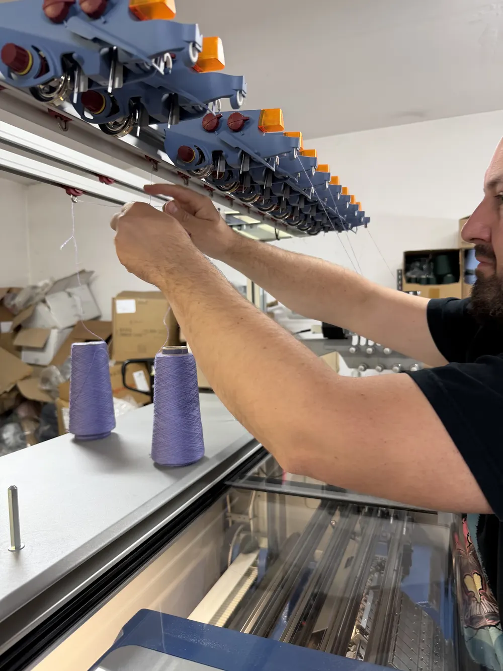 Working at the knitting machine — loading yarn at the BerryBoat mill